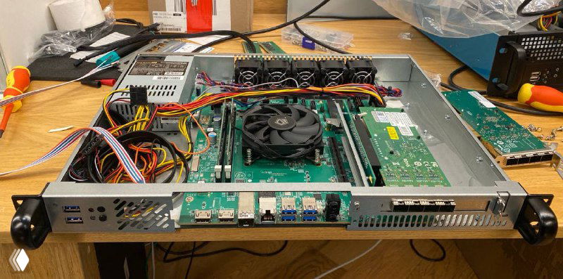 Фронтальная панель и внутренняя часть 1U-корпуса прототипа маршрутизатора: порты на передней панели, вентиляторы и подключённые кабели на рабочем столе.