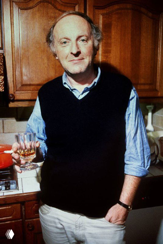 Портрет мужчины в домашней кухне, держащего бокал с напитком; кадр передаёт атмосферу лекции и дегустации, тему джина и культуры пития