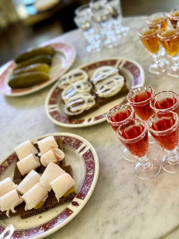 Стол с рюмками крепких напитков и тарелками с закусками на мраморной поверхности, атмосфера дегустации и барной экскурсии.