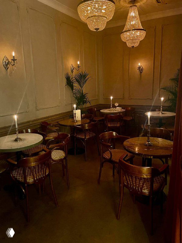Уютный зал с люстрами, круглыми столиками и зажжёнными свечами — зона для гостей в историческом баре «Медведь».
