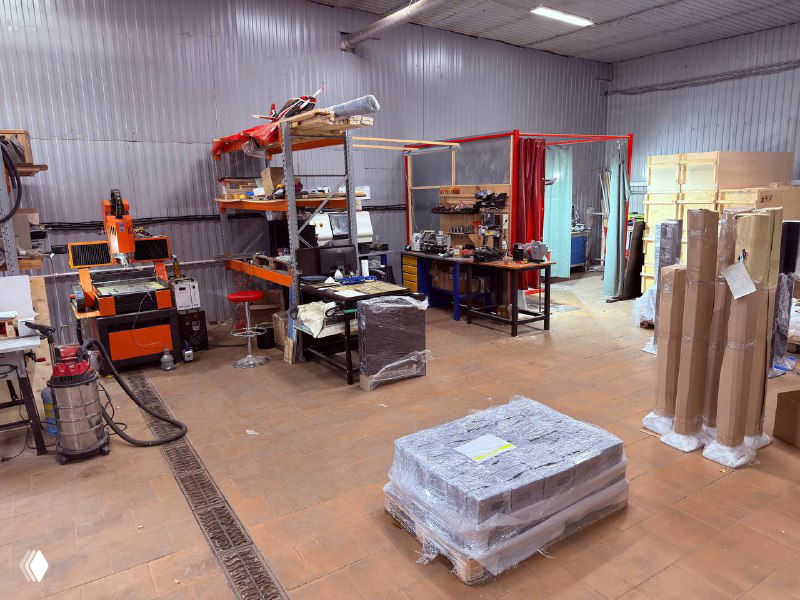 Вид производственного цеха с упакованным оборудованием на поддоне и рабочими зонами — общий план склада и линий подготовки.