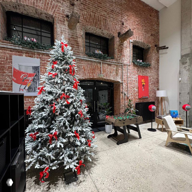 Внутренний офисный интерьер с украшенной ёлкой, кирпичной стеной, столом для настольного футбола и креслами