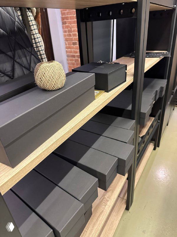 Ряд сложенных черных подарочных коробок на металлической полке, видна готовая складская зона с корпоративными наборами.