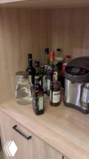 Небольшой кухонный уголок офиса: набор бутылок с напитками, кувшин с водой и электрический термопот на полке — вид зоны отдыха для сотрудников.