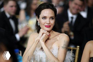 Анджелина Джоли в вечернем образе на светском мероприятии: портрет в фас, видны серьги, макияж и элегантная причёска.