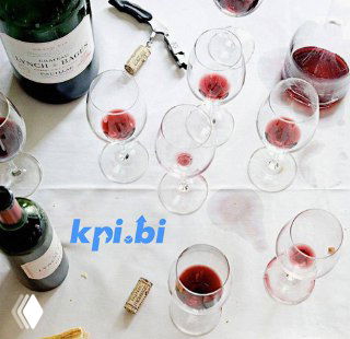 Вид сверху: бокалы с красным вином, две бутылки и пробки на белом столе; виден логотип kpi.bi — ужин и обсуждение бизнеса
