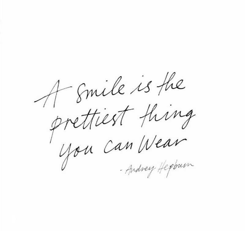 Минималистичная рукописная английская цитата на белом фоне: «A smile is the prettiest thing you can wear», акцент на улыбке и сервисе.