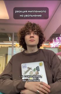 Кадр молодого человека в салонной/офисной зоне с стикерами на одежде; на фото подпись «реакция миллениала на увольнение», эмоциональный ракурс.