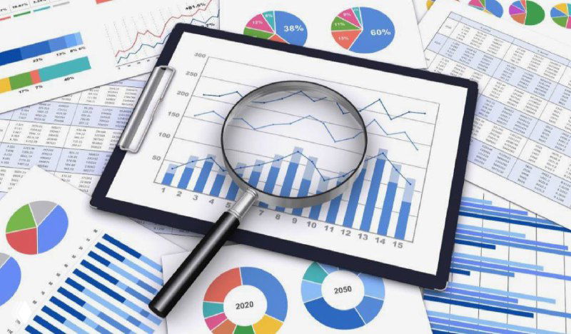 Диаграммы и графики на листах и планшете с увеличительным стеклом, символизирующие анализ прибыли и KPI в салонах