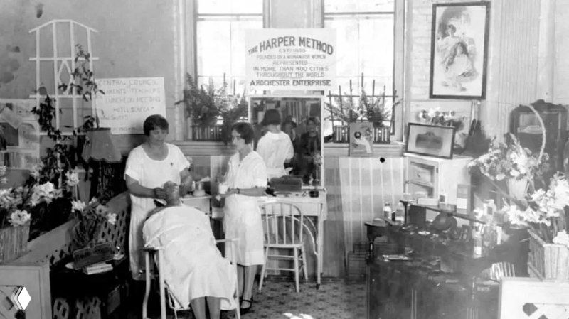 Чёрно-белая историческая фотография одного из салонов Матильды Харпер: интерьер с клиентками, мастерами, креслами и табличкой «Harper Method».