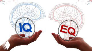 Иллюстрация: две руки держат сферы с подписями IQ (синяя) и EQ (красная) на фоне схематичных изображений мозга, символизируя отличие интеллекта и эмоционального интеллекта.