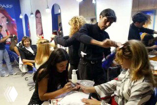 Интенсивная работа в салоне красоты: мастера одновременно делают маникюр и причёски клиентам в торговом центре Каракаса.