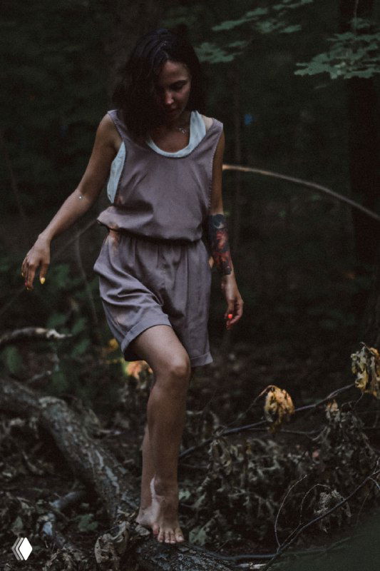 Девушка в лёгком платье идёт босиком по лесной подстилке, естественная поза и тёплая зелёная гамма подчёркивают атмосферу уединения и искренности.