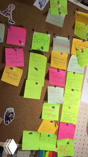 Пробковая доска с множеством разноцветных стикеров и заметок над столом — пример визуальной системы напоминаний и организации задач автора.