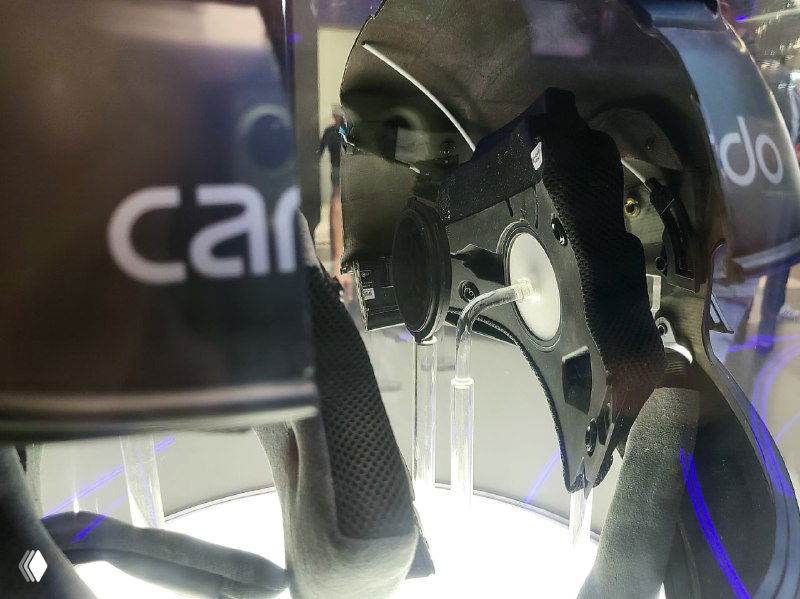Вид внутри шлема Cardo Beyond: подкладка, интегрированные динамики и крепления гарнитуры на фоне брендовой экспозиции Cardo.