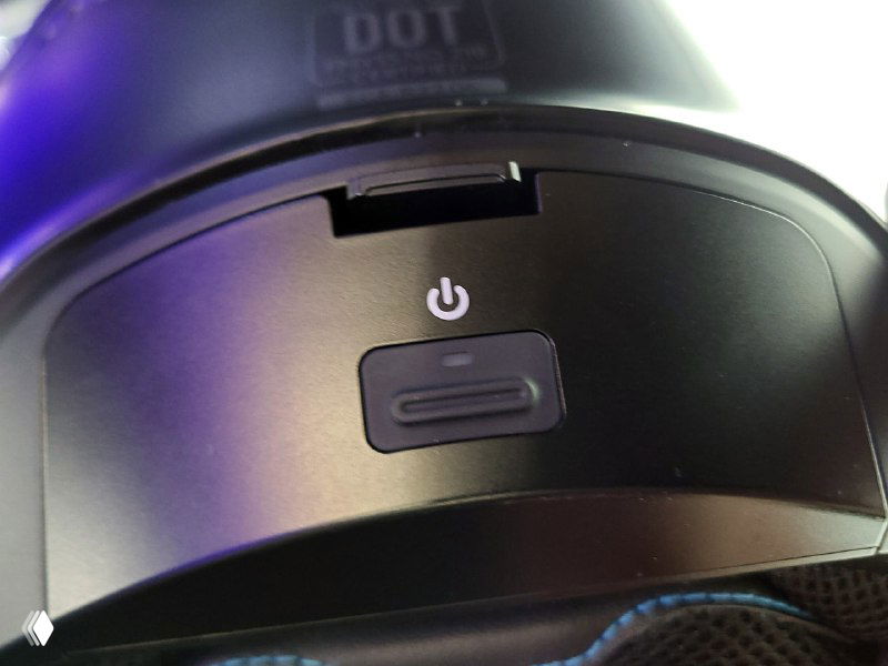 Крупный план правой боковой части шлема: кнопка питания и встроенные органы управления на внешней скорлупе Cardo Beyond, видны рёбра корпуса.