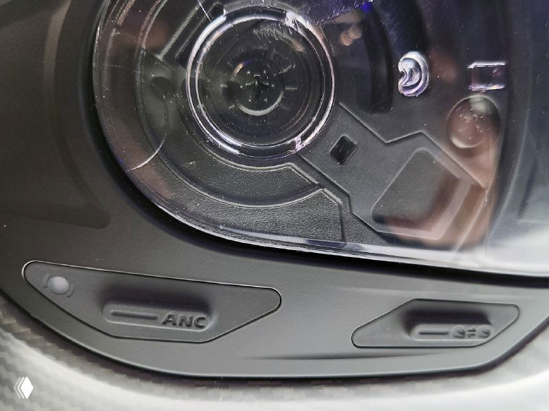 Кнопки ANC и управления на нижней кромке шлема Cardo Beyond — селекторы и индикаторы расположены у края визора, крупный план деталей.