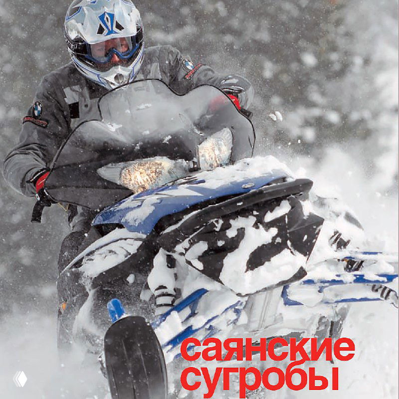 Райдер на снегоходе Yamaha в сильный снегопад: видно переднюю часть синего снегохода и шлем райдера на фоне заснеженных ёлок, кадр из тестовой поездки в Саянах.