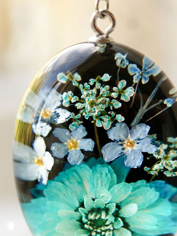 Овальная декоративная подвеска с нежными засушенными цветами и элементами кружевного рисунка, фото крупным планом.