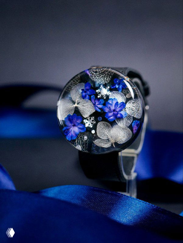 Круглая подвеска-брелок с синими и белыми высушенными гортензиями в прозрачной смоле на тёмном фоне, аккуратно снятая для показа деталей.