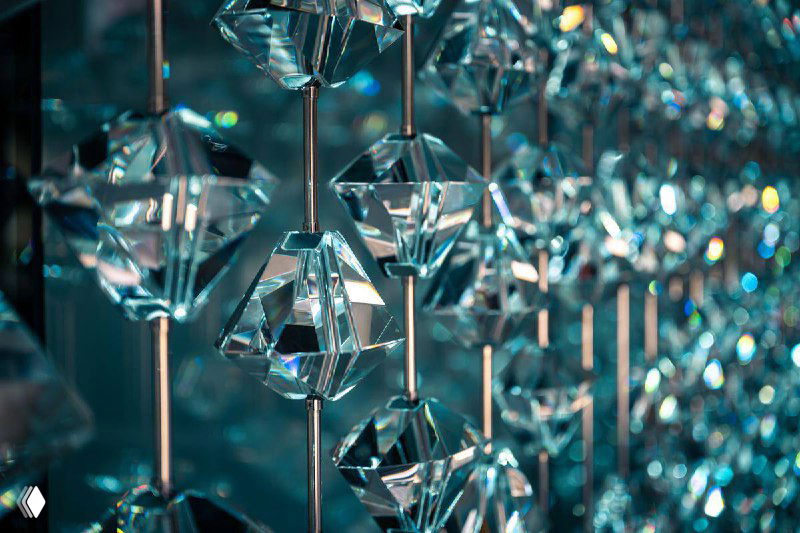 Крупный план ряда висящих кристаллических подвесок, похожих на бриллианты, с ярким блеском, искрящимися отражениями и холодными синими тонами.