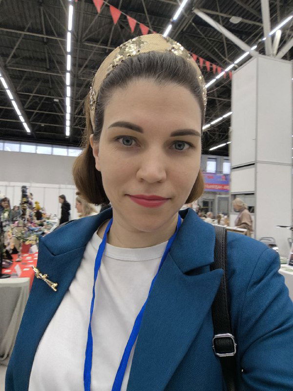 Портрет автора в деловом пиджаке с бейджем на фоне зала форума; селфи демонстрирует деловой образ и участие в мероприятии.