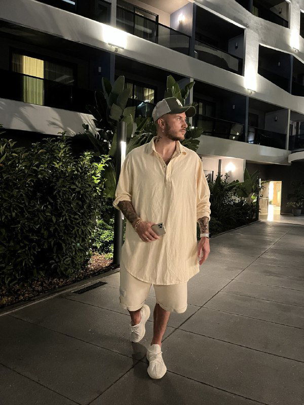 Фотография мужчины в свободном повседневном стиле на улице у жилого комплекса вечером, демонстрирует непринуждённый образ и предпочтение casual‑одежды.