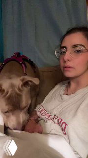 Человек в очках сидит на диване рядом с крупной собакой; собака близко к руке автора, домашняя сцена без указания личности.