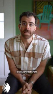 Кадр с видеоселфи: мужчина в короткой рубашке сидит в комнате, видно лицо и плечи на фоне домашнего интерьера, фронтальный ракурс