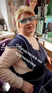 Портрет парикмахера Елены в салоне: кадр из Reels, она в ярких очках на фоне полок с товарами и профессиональной рабочей обстановкой.