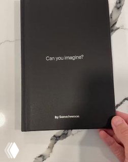 Обложка книги Soren Iverson с надписью «Can you imagine?» на чёрной корочке; книга в руке на мраморной поверхности, демонстрация печатного формата идей.