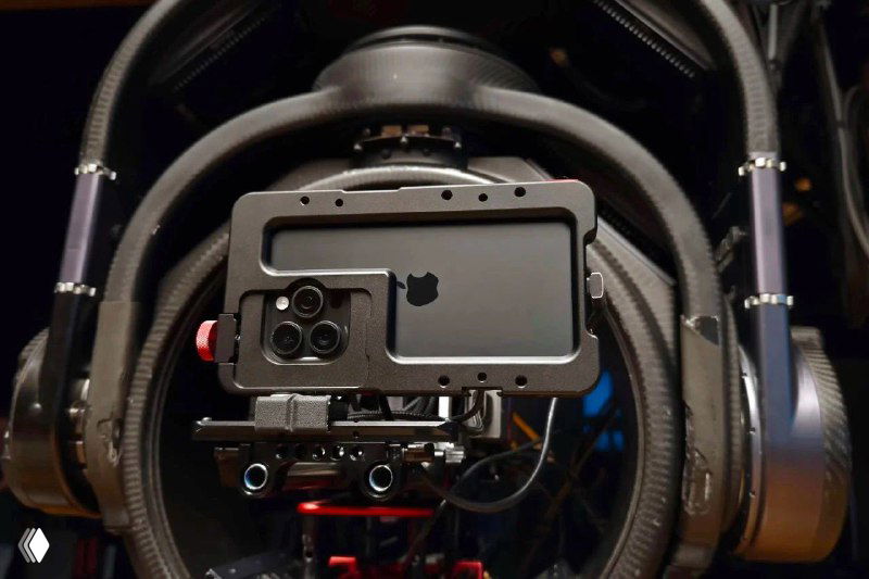 Крупный план iPhone, закреплённого в монтажном корпусе на профессиональном риге с аксессуарами, подчёркивающий постановочную съёмку ролика Apple.