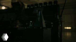 Кадр из рекламного ролика Apple: тёмное индустриальное помещение, крупный план механики и оборудования, атмосферный свет и тень.