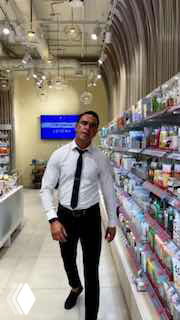 Бортпроводник в форме стоит в косметическом магазине; вертикальный кадр показывает полки с товарами и интерьер точки, подчёркивая контекст бренд‑интеграции.