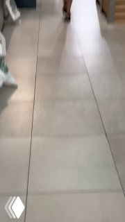 Вертикальный кадр из ролика: плиточный пол супермаркета, видна полоса прохода и часть ног покупателя — типичная сцена нативного посева.