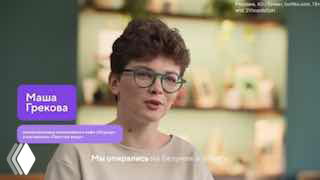 Кадр интервью из видеопроекта: женщина в очках говорит в студийной обстановке на фоне размытых декораций и графики с именем.