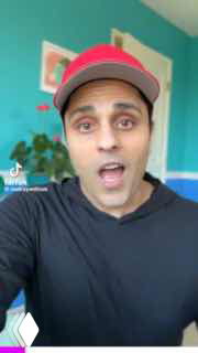 Крупный план ведущего в кепке в вертикальном видео: автор говорит в камеру на ярком фоне, типичный кадр для короткого формата TikTok/YouTube.