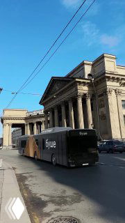 Городской уличный кадр: автобус с брендингом «буше» на фоне классического здания и синего неба; пример визуальной подачи продукта в реальной среде