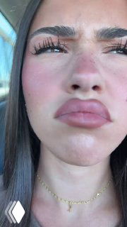 Крупный план лица молодой женщины в машине: выразительные ресницы, подчеркнутые губы, прищур и недовольное выражение, солнечный свет в окне.