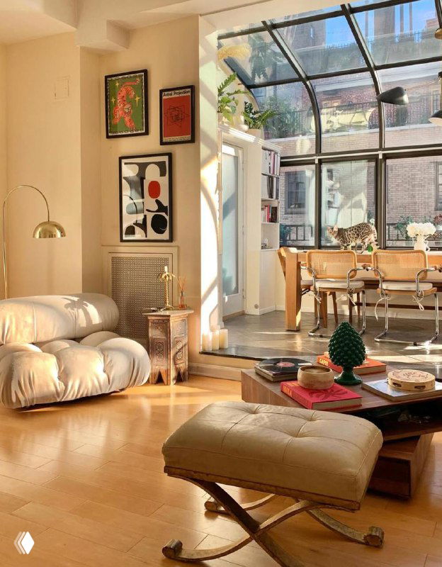 Светлая гостиная с большими окнами, уютной мебелью и отдельной группой плакатов на стене — пример гармонии постеров и интерьера.