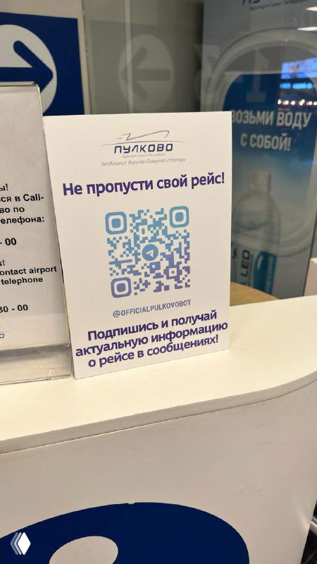 Табличка с QR‑кодом и надписью «Не пропусти свой рейс» на стойке в Пулково; фото демонстрирует офлайн‑приём SMO для подписки на бота.
