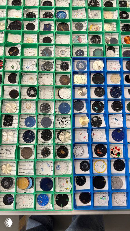 Фотография ряда кастомных циферблатов завода «Луч»: аккуратно уложенные в лотки разноцветные циферблаты с разными принтами и оформлением, вид вблизи.