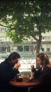 Мужчина и женщина за столиком в кафе пьют напитки; сцена выглядит атмосферно и кинематично — подходящая для брендового ролика в соцсетях.