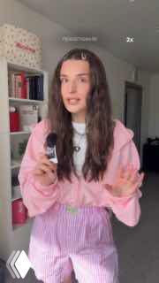 Блогерша в комнате держит товар в руках на фоне полок с книгами; кадр ролика, где акцент сделан на продукте и подаче автора.