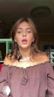 Молодая женщина говорит в камеру в формате вертикального видео, выражая историю об увольнении и переработках в рабочем окружении.