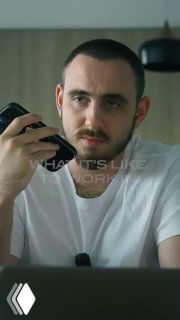 Мужчина держит телефон у уха и смотрит в камеру — сцена из ролика о повседневных задачах агентства и телефонных разговорах с клиентами.