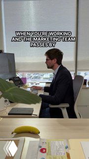 Офисный сотрудник в очках сидит за столом, окно за спиной; на кадре текст про «когда команда маркетинга проходит мимо» — мем о восприятии маркетинга внутри компании.