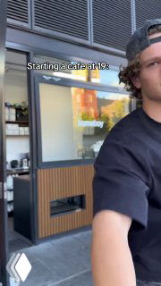 Юноша в кепке на фоне витрины и отражений, прогулочный кадр в ролике о запуске кафе, ощущается уличная атмосфера и ранняя стадия бизнеса.