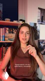 Кадр из видео: молодая женщина говорит в камеру на фоне книжной полки — вероятно сотрудница, рассказывающая про систематические задержки зарплат.