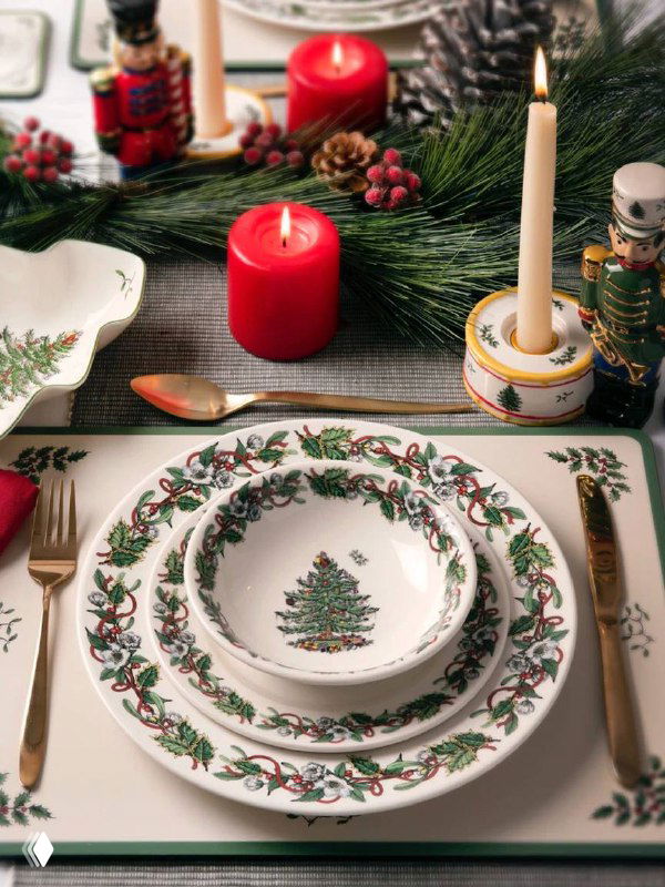 Сервировка стола: тарелка и миска Spode из коллекции «Рождественская ель», свеча и праздничные декорации в традиционных красно‑зелёных тонах.